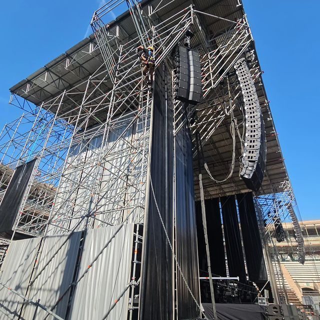Técnico haciendo rigging en la estructura de un escenario de conciertos