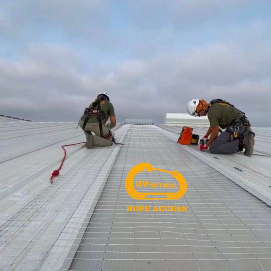 Dos técnicos instalando protección sobre lucernarios en una cubierta industrial